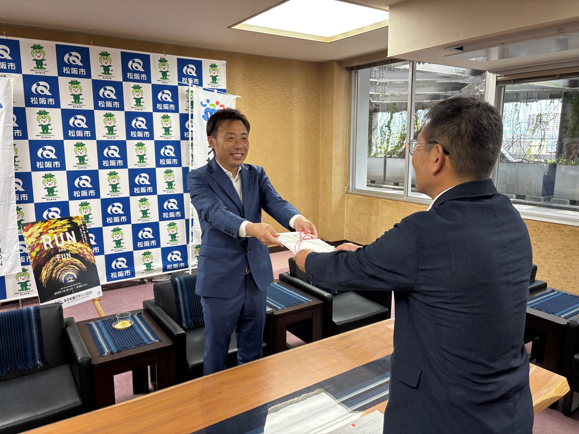 松阪市役所にて行われた「みえ松阪マラソン」の協賛品贈呈式に参加する瀬古食品グループ代表の瀬古守伸氏と松阪市の竹上真人市長